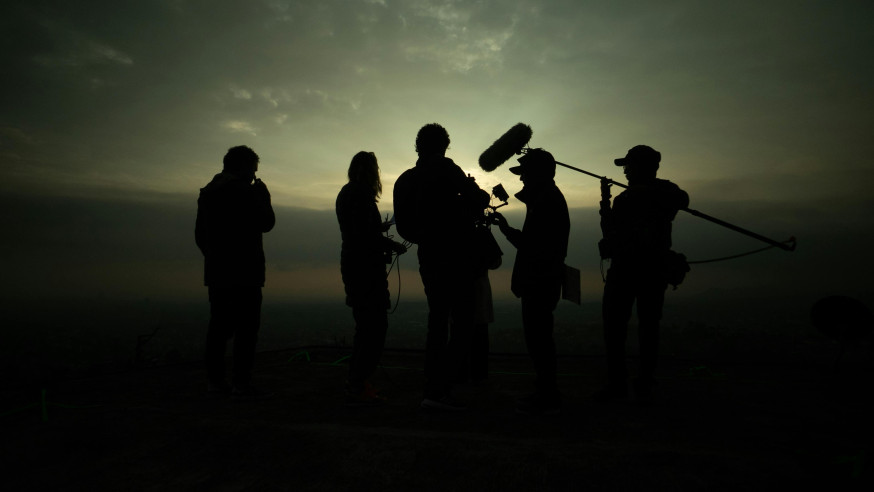Silhouet van filmcrew met boom-microfoon bij zonsondergang voor geluid opnemen bij video