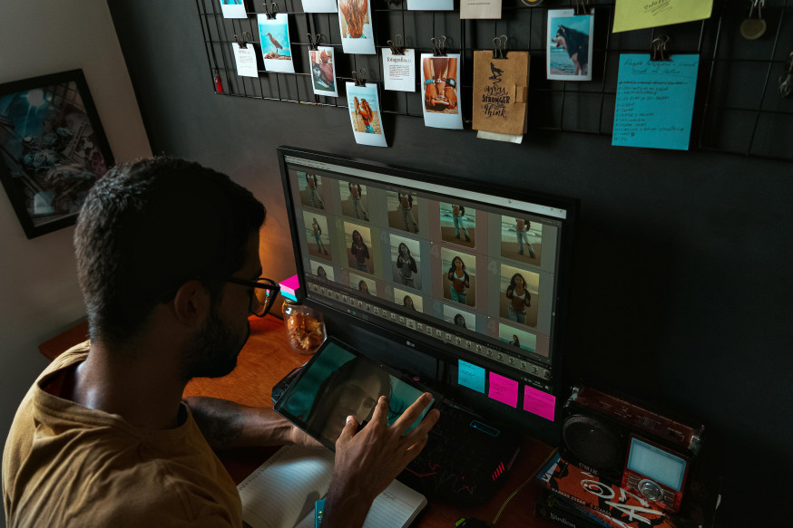 Afbeelding: fotograaf bewerkt beelden aan bureau met groot scherm en tekentablet in neutrale werkhouding voor betere ergonomie als fotograaf