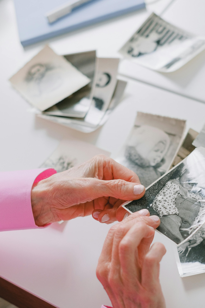Afbeelding: Handen sorteren prints in drie stapels (ja, nee, misschien) op tafel, een fysieke selectiemethode bij het maken van een overtuigend fotoboek