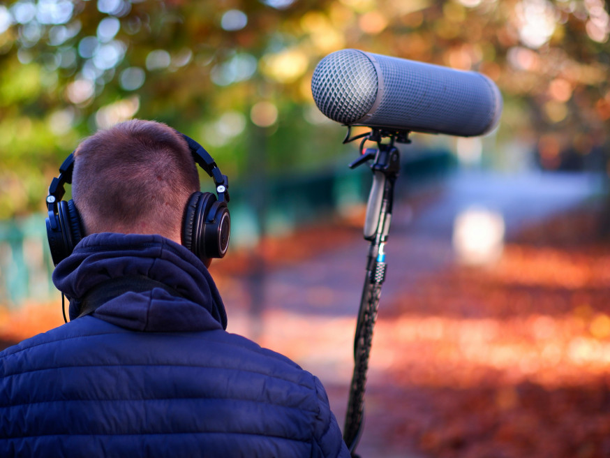 Geluidstechnicus monitort audio met koptelefoon en boom-microfoon tijdens video-opname